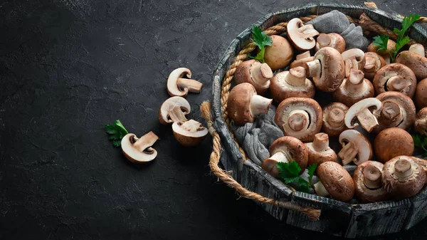 Mushrooms in a wooden box on the old table. Champignons Top view. Free copy space.