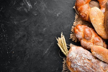 Ekmek çeşitleri ve siyah taş arka plan üzerinde pişirme. Üst te. Metniniz için boş alan.