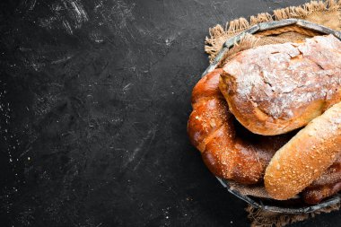 Ekmek çeşitleri ve siyah taş arka plan üzerinde pişirme. Üst te. Metniniz için boş alan.
