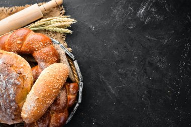 Ekmek çeşitleri ve siyah taş arka plan üzerinde pişirme. Üst te. Metniniz için boş alan.