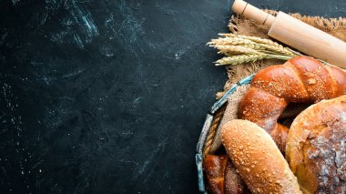 Ekmek çeşitleri ve siyah taş arka plan üzerinde pişirme. Üst te. Metniniz için boş alan.
