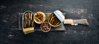Kavanozda füme sprats. Balık. Siyah bir arka plan üzerinde. üst görünüm. Ücretsiz kopyalama alanı.