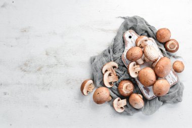 Beyaz ahşap arka plan üzerinde mantarlar. Champignons Üst görünüm. Ücretsiz kopyalama alanı.