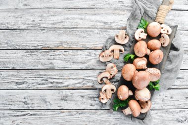 Beyaz ahşap arka plan üzerinde mantarlar. Champignons Üst görünüm. Ücretsiz kopyalama alanı.