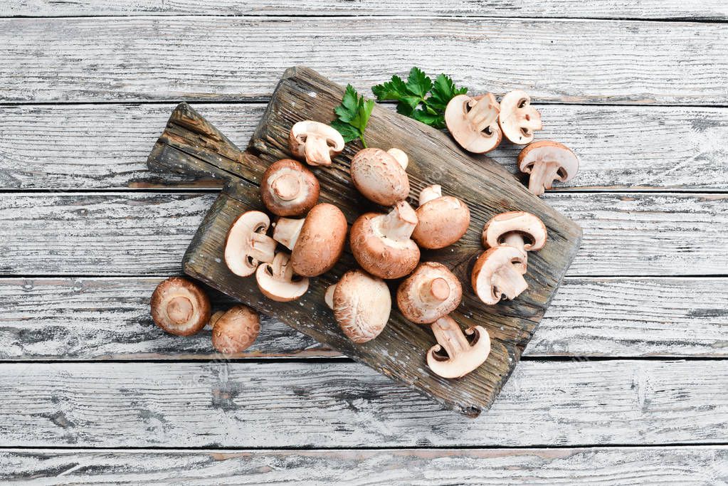 Mushrooms on a white wooden background. Champignons Top view. Free copy space.
