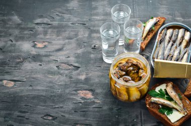 Sprats ve votka ile sandviç. Yağda sprat. Siyah bir arka plan üzerinde. üst görünüm. Ücretsiz kopyalama alanı.