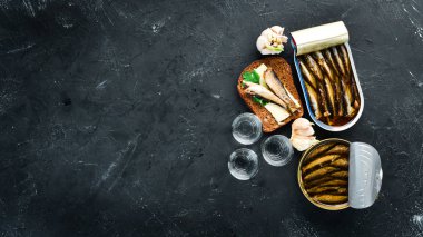 Sprats ve votka ile sandviç. Yağda sprat. Siyah bir arka plan üzerinde. üst görünüm. Ücretsiz kopyalama alanı.