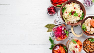 Beyaz mutfak masasında sebze ve mantar turşusu. Lahana, mantar, salatalık, karnabahar. Üst te. Metniniz için boş alan.