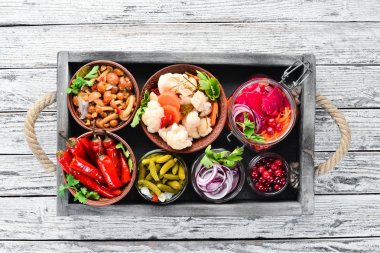 Beyaz mutfak masasında sebze ve mantar turşusu. Lahana, mantar, salatalık, karnabahar. Üst te. Metniniz için boş alan.