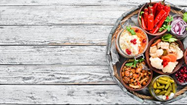 Beyaz mutfak masasında sebze ve mantar turşusu. Lahana, mantar, salatalık, karnabahar. Üst te. Metniniz için boş alan.