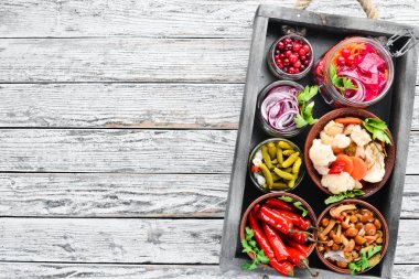 Beyaz mutfak masasında sebze ve mantar turşusu. Lahana, mantar, salatalık, karnabahar. Üst te. Metniniz için boş alan.