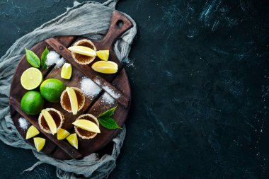 Siyah taş arka plan üzerinde kireç ve tuz ile altın tekila. Üst te. Metniniz için boş alan.