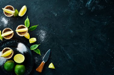 Siyah taş arka plan üzerinde kireç ve tuz ile altın tekila. Üst te. Metniniz için boş alan.