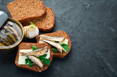 Sprat'la sandviç. Yağda sprat. Siyah bir arka plan üzerinde. üst görünüm. Ücretsiz kopyalama alanı.