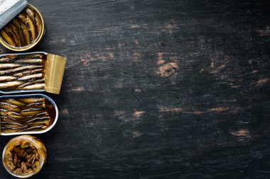 Yağda sprats çeşitleri. Füme balık Siyah bir arka plan üzerinde. üst görünüm. Ücretsiz kopyalama alanı.