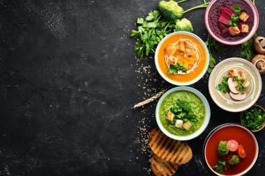 Renkli sebze kremalı çorba çeşitleri. Diyet yemekleri. Siyah taş bir arka plan üzerinde. Üst te. Ücretsiz kopyalama alanı