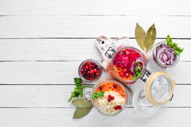 Beyaz bir yemek masasında bir kavanozda lahana turşusu. Lahana, karnabahar. Üst te. Metniniz için boş alan.