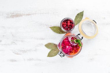 Beyaz bir yemek masasında bir kavanozda lahana turşusu. Lahana, karnabahar. Üst te. Metniniz için boş alan.