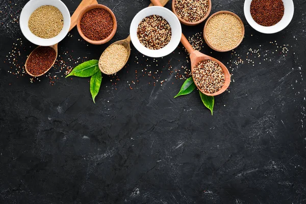 Kırmızı, beyaz ve kahverengi kinoa seti. Siyah bir arka planda. Üst Manzara. Boş kopyalama alanı.