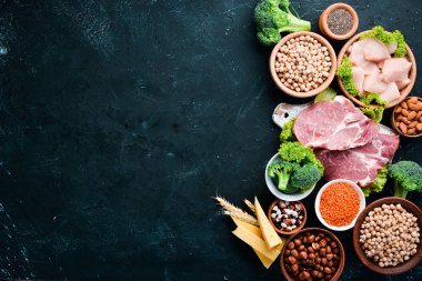 Sağlıklı protein kaynağı ve vücut geliştirme gıdaların çeşitleri. Et, tavuk filetosu, brokoli, fasulye, peynir, yumurta, buğday. Taş arka planda.