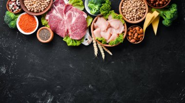 Sağlıklı protein kaynağı ve vücut geliştirme gıdaların çeşitleri. Et, tavuk filetosu, brokoli, fasulye, peynir, yumurta, buğday. Taş arka planda.