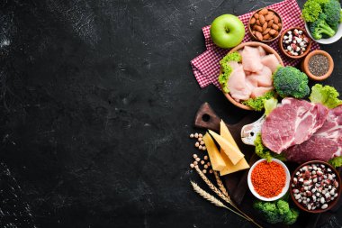 Sağlıklı protein kaynağı ve vücut geliştirme gıdaların çeşitleri. Et, tavuk filetosu, brokoli, fasulye, peynir, yumurta, buğday. Taş arka planda.