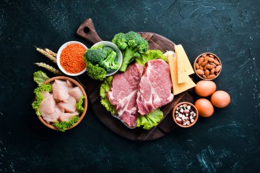 Sağlıklı protein kaynağı ve vücut geliştirme gıdaların çeşitleri. Et, tavuk filetosu, brokoli, fasulye, peynir, yumurta, buğday. Taş arka planda.