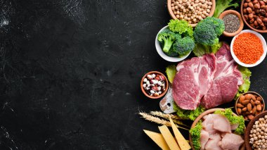 Sağlıklı protein kaynağı ve vücut geliştirme gıdaların çeşitleri. Et, tavuk filetosu, brokoli, fasulye, peynir, yumurta, buğday. Taş arka planda.