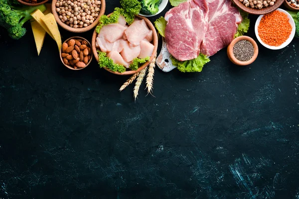 Sağlıklı protein kaynağı ve vücut geliştirme gıdaların çeşitleri. Et, tavuk filetosu, brokoli, fasulye, peynir, yumurta, buğday. Taş arka planda.