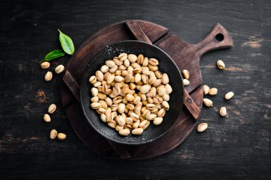 Siyah bir arka plan üzerinde bir kase tuz antep fıstığı. Üst te. Metniniz için boş alan.