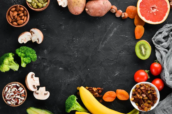 The food contains natural potassium. K: Potatoes, mushrooms, banana, tomatoes, nuts, beans, broccoli, avocados. Top view. On a black background.