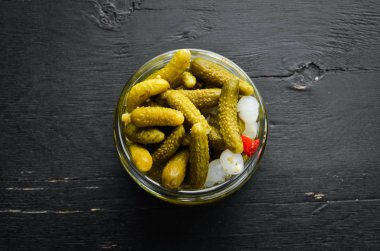 Siyah ahşap mutfak masasında bir kavanozda marine salatalık. Üst te. Metniniz için boş alan.