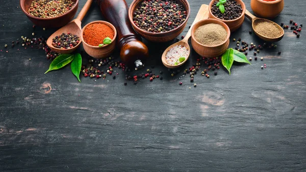 A set of peppers. Black pepper, colored pepper, ground pepper, dried chili pepper. Top view. On a black background. free space for your text.