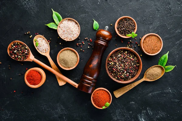 A set of peppers. Black pepper, colored pepper, ground pepper, dried chili pepper. Top view. On a black background. free space for your text.