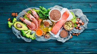 Omega 3 içeren gıdalar. Vitamin Sağlıklı gıdalar: avokado, balık, karides, brokoli, keten, fındık, yumurta, maydanoz. Üst te. Metniniz için boş alan. Mavi ahşap arka planda.