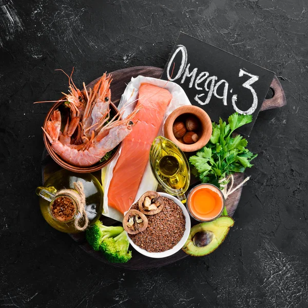 Food with natural vitamin Omega 3. Healthy food: fish, shrimp, broccoli, flax, nuts, egg, parsley. Top view. Free space for your text. On a black background.