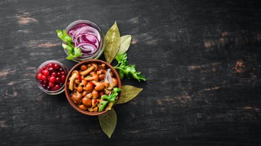 Siyah ahşap mutfak masasında bir kavanozda marine mantar. Üst te. Metniniz için boş alan.