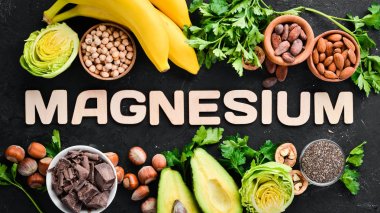Doğal magnezyum içeren gıdalar. Mg: Çikolata, muz, kakao, fındık, avokado, brokoli, badem. Üst te. Siyah arka planda.