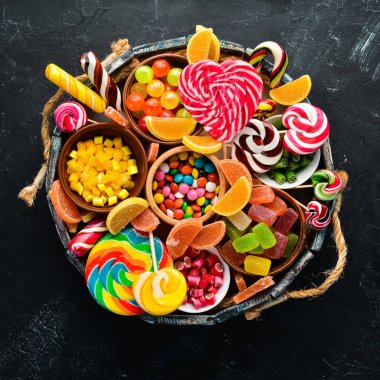 Ahşap bir kutuda renkli şekerler, jöle ve marmelat. Tatlı. Eski arka planda. Üst te. ücretsiz kopyalama alanı.