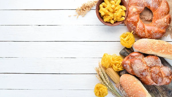 Gluten free food. Various pasta, bread, snacks and flour on a white wooden background. Top view. Free space for your text.