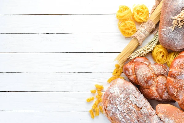 Gluten free food. Various pasta, bread, snacks and flour on a white wooden background. Top view. Free space for your text.