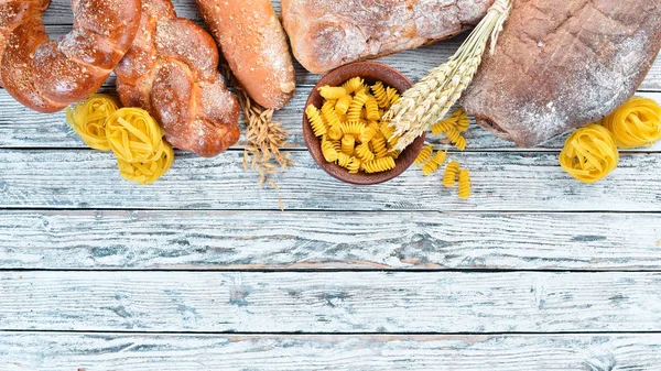 Gluten free food. Various pasta, bread, snacks and flour on a white wooden background. Top view. Free space for your text.