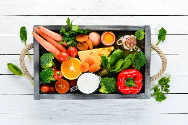 Healthy foods, fruits and vegetables. Broccoli, Carrots, milk, cheese, spinach, dried apricots, parsley, tomatoes. Top view.