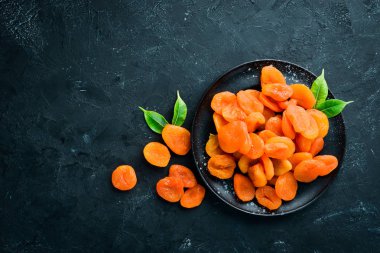 Siyah bir arka plan üzerinde bir kase kuru kayısı. Üst te. Metniniz için boş alan.