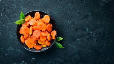 Siyah bir arka plan üzerinde bir kase kuru kayısı. Üst te. Metniniz için boş alan.