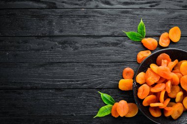 Siyah bir arka plan üzerinde bir kase kuru kayısı. Üst te. Metniniz için boş alan.