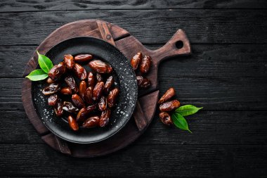 Siyah bir arka plan üzerinde bir kase kuru tarih. Kurutulmuş meyve Üst görünüm. Metniniz için boş alan.