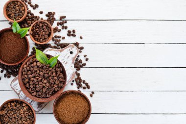 Öğütülmüş kahve ve kahve çekirdekleri. Beyaz ahşap bir arka plan üzerinde. Üst te. Metniniz için boş alan.