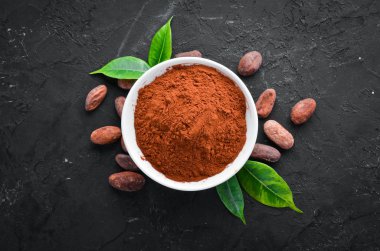 Bir kase ve kakao fasulyesinde kakao tozu. Siyah bir arka plan üzerinde. Üst te. Ücretsiz kopyalama alanı.