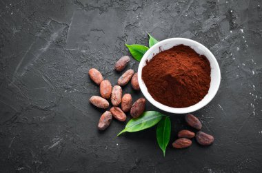 Bir kase ve kakao fasulyesinde kakao tozu. Siyah bir arka plan üzerinde. Üst te. Ücretsiz kopyalama alanı.